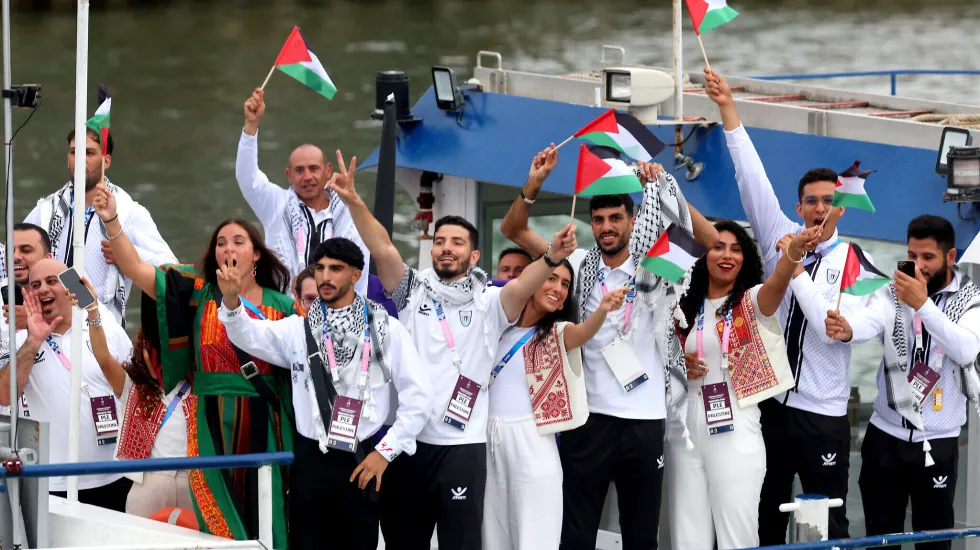 Athletes of Team Palestine wave flags on the athletes' parade team boat along the River Seine during the opening ceremony of the Olympic Games Paris 2024 on July 26, 2024 in Paris, France